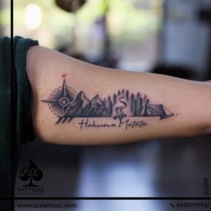 Travel tattoo to represent stories of places traveled and dreams of the bucket list that lists all the places that are in the bucket list. With a Compass to navigate the path as you move forward, Mountains and Forest for the sense of freedom with the thrill of trekking. Bonfire and a Tent to show the love for a night under the stars and the quote ‘Hakuna Matata’ to live a worry-free life sums up the tattoo story perfectly.