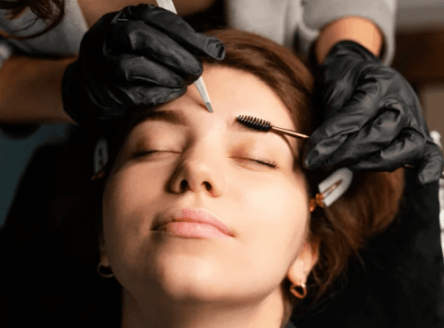 high-angle-female-clinician-doing-eyebrow-treatment-woman 1